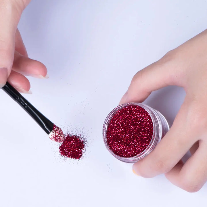 a person holding a brush and glitter in their hand